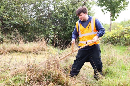 Participants supported in scything one of the natural meadows in Hounslow Heath