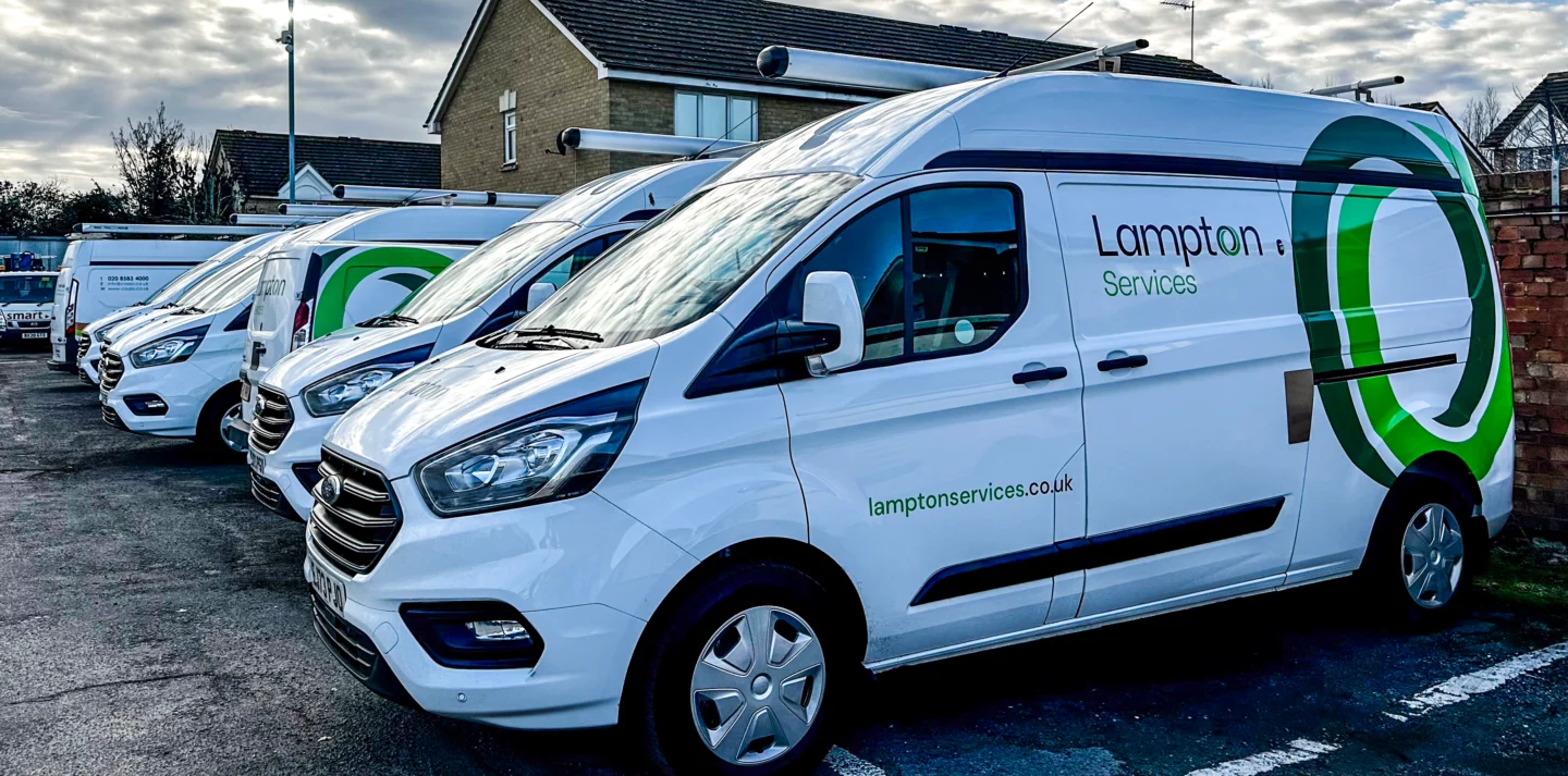 A row of white service vans with “Lampton Services” branding.