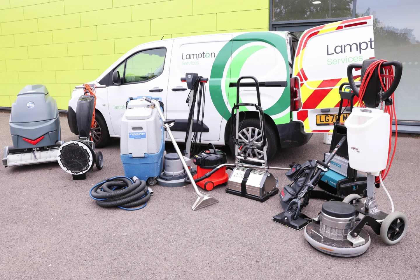 Various cleaning equipment displayed in front of a Lampton Services van